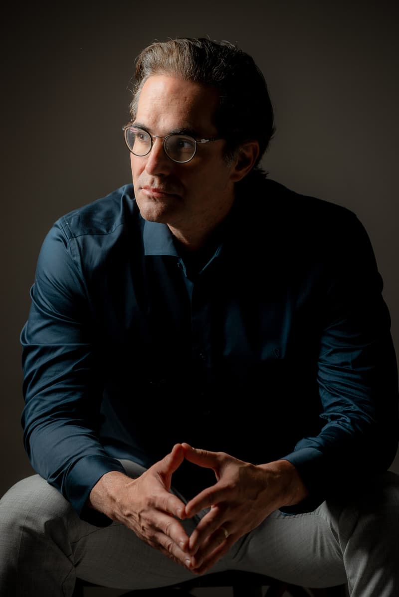 Dr. Daniel Botelho, cirurgião plástico, sentado com as mãos unidas